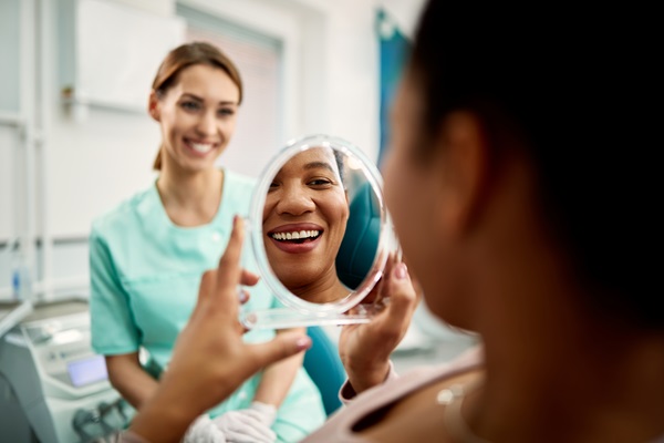 Close up of black woman looking at her teeth after dental procedure at dentist's office.