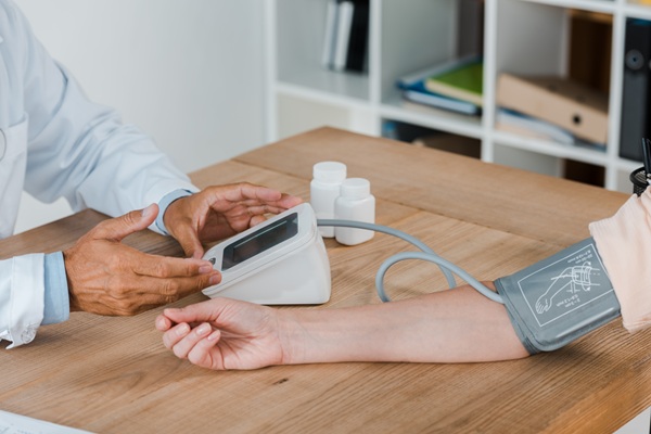 doctor gesturing while measuring blood pressure of woman