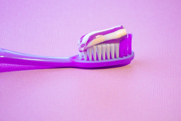 toothbrush with purple toothpaste and purple background