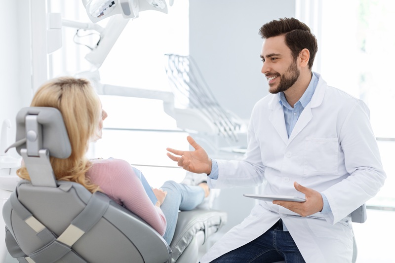 Male dentist showing female patient x-ray on digital tablet