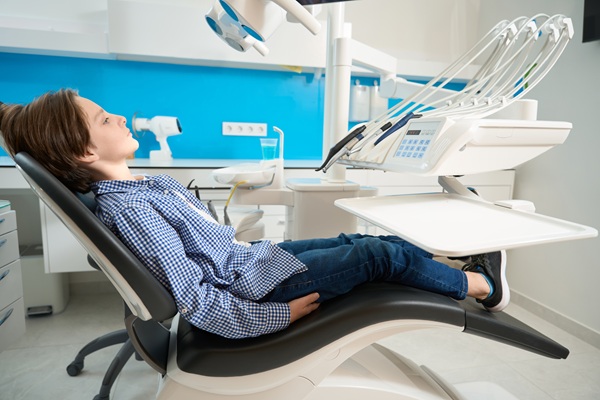 Concentrated boy in a plaid shirt sits calmly in a dental chair, special equipment is around
