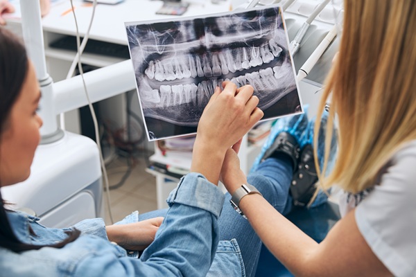Attentive patient pointing at roentgen photo while being on professional consultation about wisdom tooth